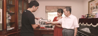 李绍宽（右）拿出在人民大会堂领取博士学位证书时的合影，欧博官网指着当年的自己，与青年师生代表交流他为师为学的经验，同时鼓励年轻学子将个人的成长融入祖国的发展之中。（东华大学供图）